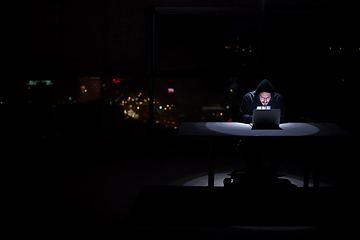 Image showing hacker using laptop computer while working in dark office