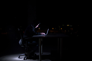 Image showing hacker using laptop computer while working in dark office