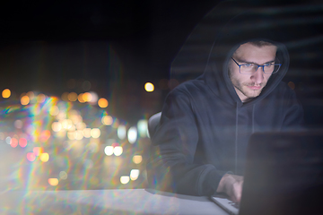 Image showing hacker using laptop computer while working in dark office