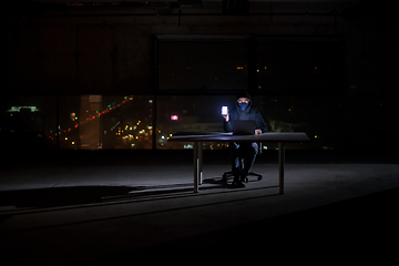 Image showing hacker using laptop computer while working in dark office