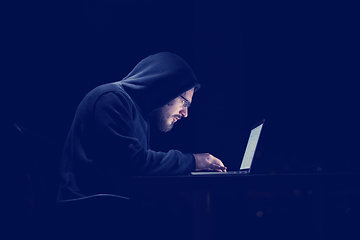 Image showing hacker using laptop computer while working in dark office