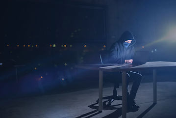 Image showing hacker using laptop computer while working in dark office