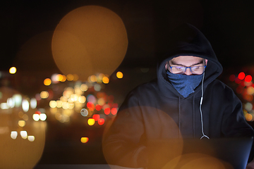 Image showing hacker using laptop computer while working in dark office