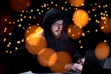 Image showing hacker using laptop computer while working in dark office