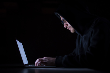 Image showing hacker using laptop computer while working in dark office