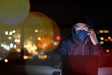 Image showing hacker using laptop computer while working in dark office