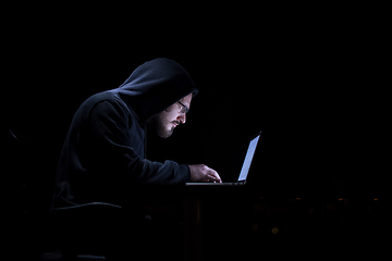 Image showing hacker using laptop computer while working in dark office