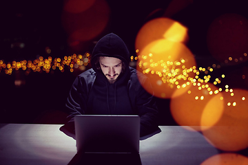 Image showing hacker using laptop computer while working in dark office