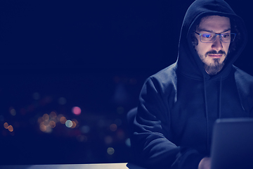 Image showing hacker using laptop computer while working in dark office