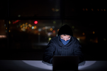 Image showing hacker using laptop computer while working in dark office