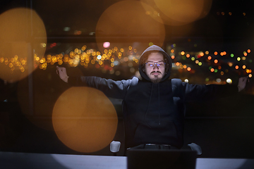 Image showing hacker using laptop computer while working in dark office