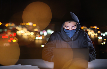 Image showing hacker using laptop computer while working in dark office