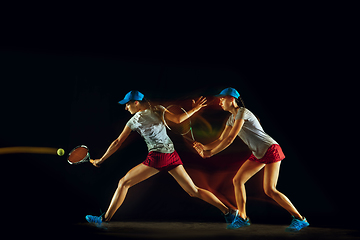 Image showing One caucasian woman playing tennis on black background in mixed light