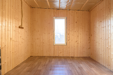 Image showing The interior of a small empty room in a country house, the walls are clapboard, linoleum is laid on the floor