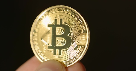 Image showing Shiny physical bitcoin in hands over sunlight