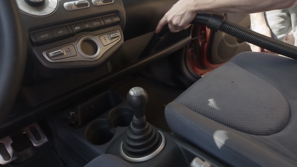 Image showing Man cleaning dirty car interior with vacuum cleaner