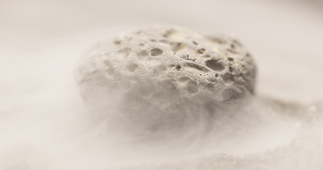 Image showing Smoke whirling around small meteorite stone