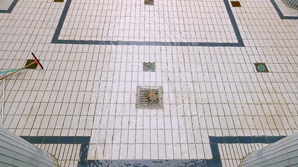 Image showing Steel drain on tiled floor with water whirling