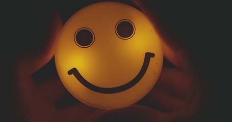 Image showing Hands holding glowing smiley head closeup footage