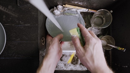 Image showing Washing dirty dishware in black sink