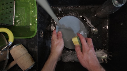 Image showing Washing dirty dishware in black sink