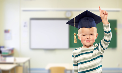 Image showing boy in mortar board pointing finger up at school