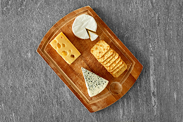 Image showing different cheeses and crackers on wooden board