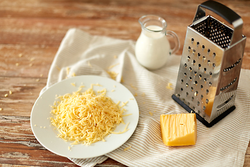 Image showing close up of grated cheese and jug of milk on table