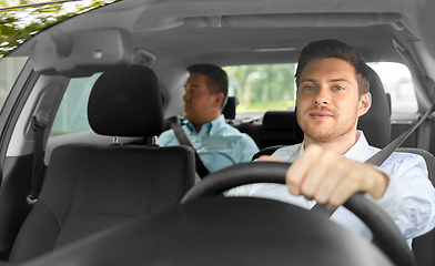 Image showing male taxi driver driving car with passenger