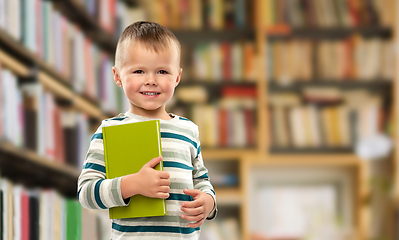 Image showing portrait of smiling boy holding book over library