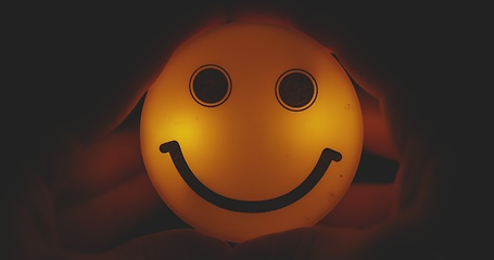 Image showing Hands holding glowing smiley head closeup footage