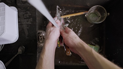 Image showing Washing dirty dishware in black sink