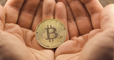 Image showing Inspecting Physical bitcoin held in hands closeup
