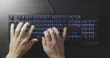 Image showing Close-up of typing male hands on illuminated keyboard