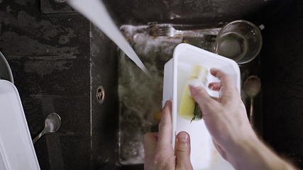 Image showing Washing dirty dishware in black sink