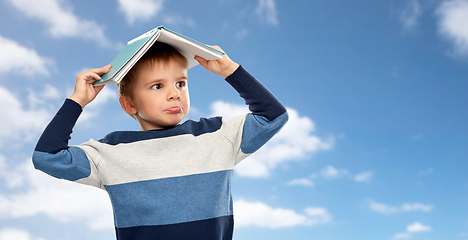 Image showing little boy with roof of book on his head over sky