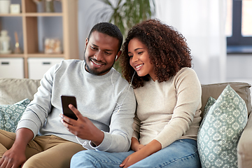 Image showing happy couple with smartphone and earphones at home