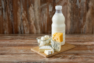 Image showing different kinds of cheese and milk on wooden board