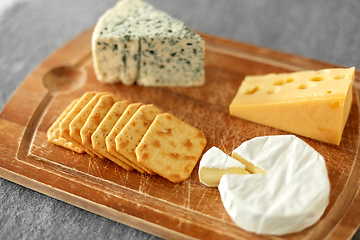 Image showing different cheeses and crackers on wooden board