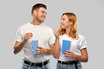 Image showing happy couple in white t-shirts eating popcorn