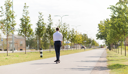 Image showing young businessman riding electric scooter outdoors