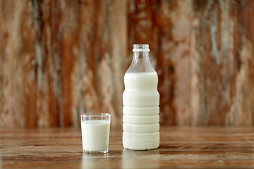 Image showing glass and bottle of milk on wooden table