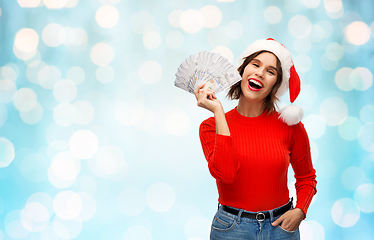Image showing happy woman in santa hat with money on christmas