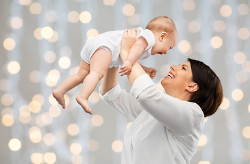 Image showing happy middle-aged mother with baby over lights