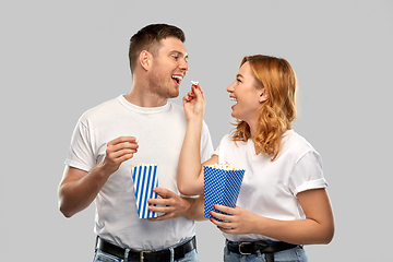 Image showing happy couple in white t-shirts eating popcorn