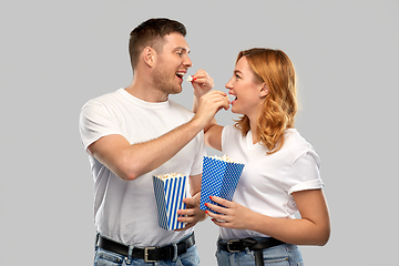 Image showing happy couple in white t-shirts eating popcorn