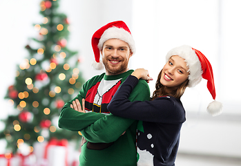 Image showing happy couple in christmas sweaters and santa hats