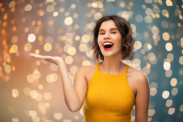 Image showing happy young woman holding something on empty hand