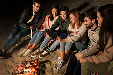 Image showing friends with tablet pc at fire on beach at night