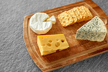 Image showing different cheeses and crackers on wooden board